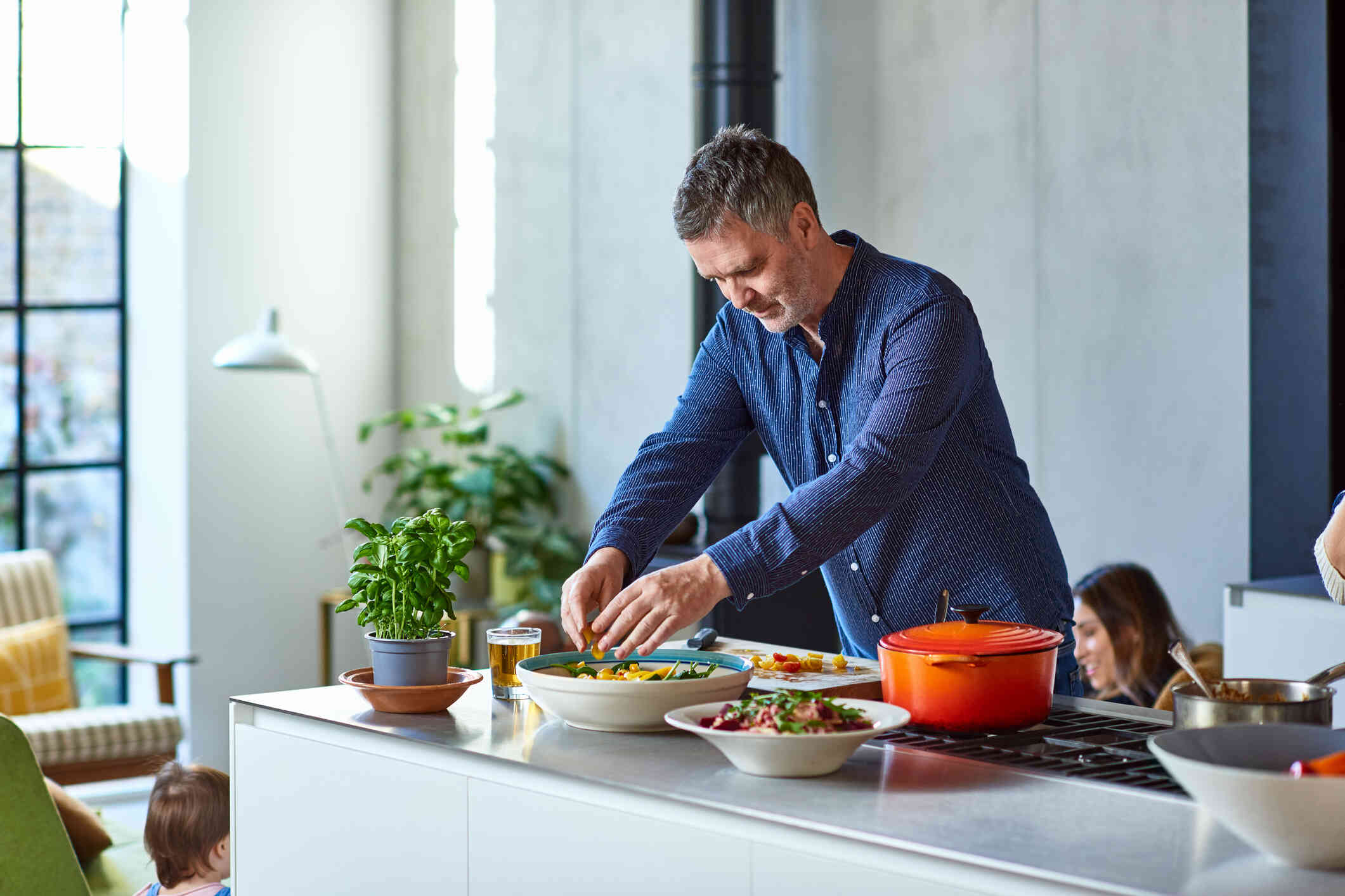 A middle aged man plates dinner while preapring food for his family at home.